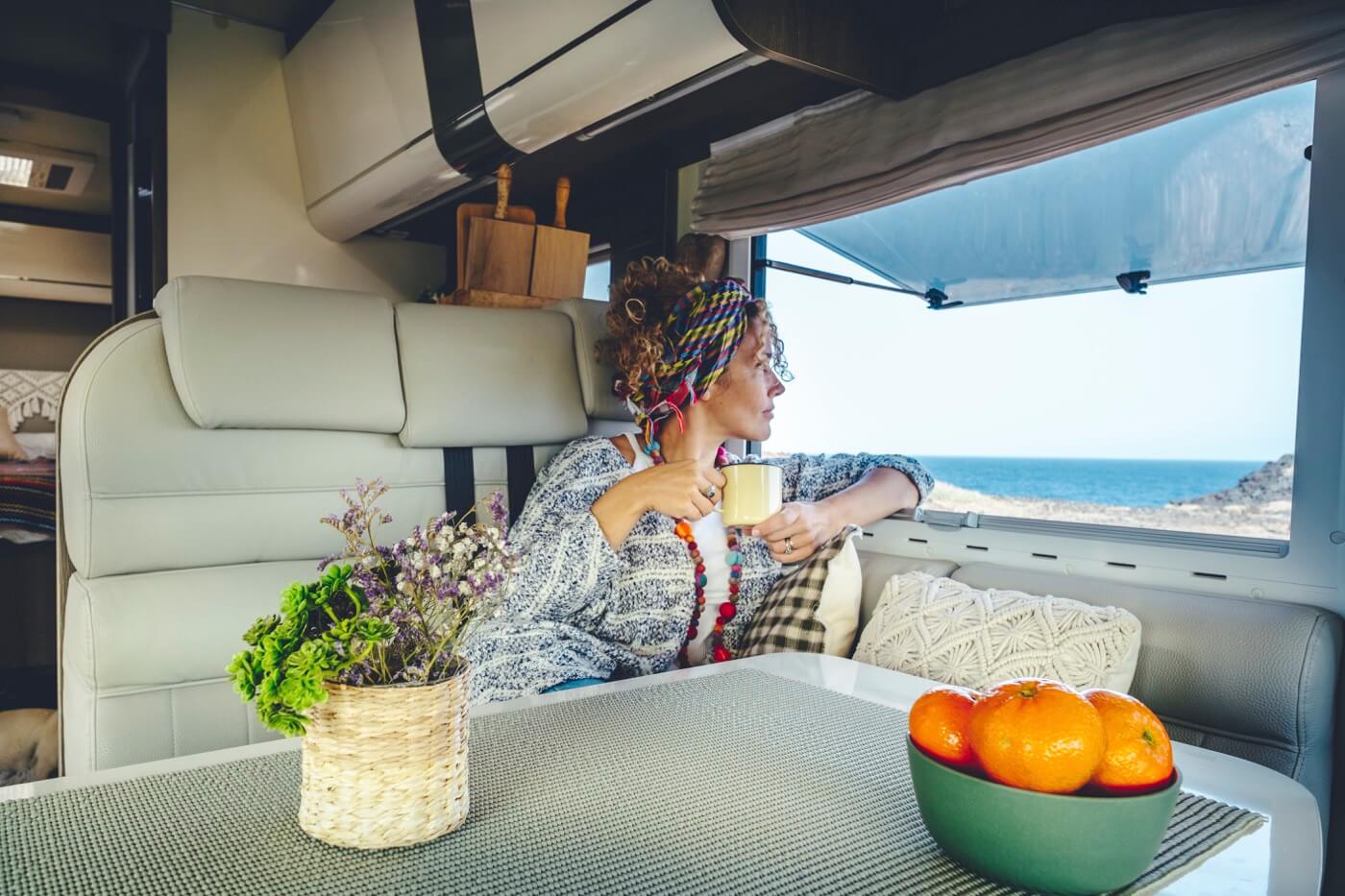 Femme buvant et profitant de la vue de la mer en vanlife.